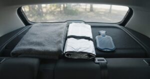 車の窓際に並べて置かれたサンシェード・毛布・湯たんぽ、夏冬双方の季節対策グッズ