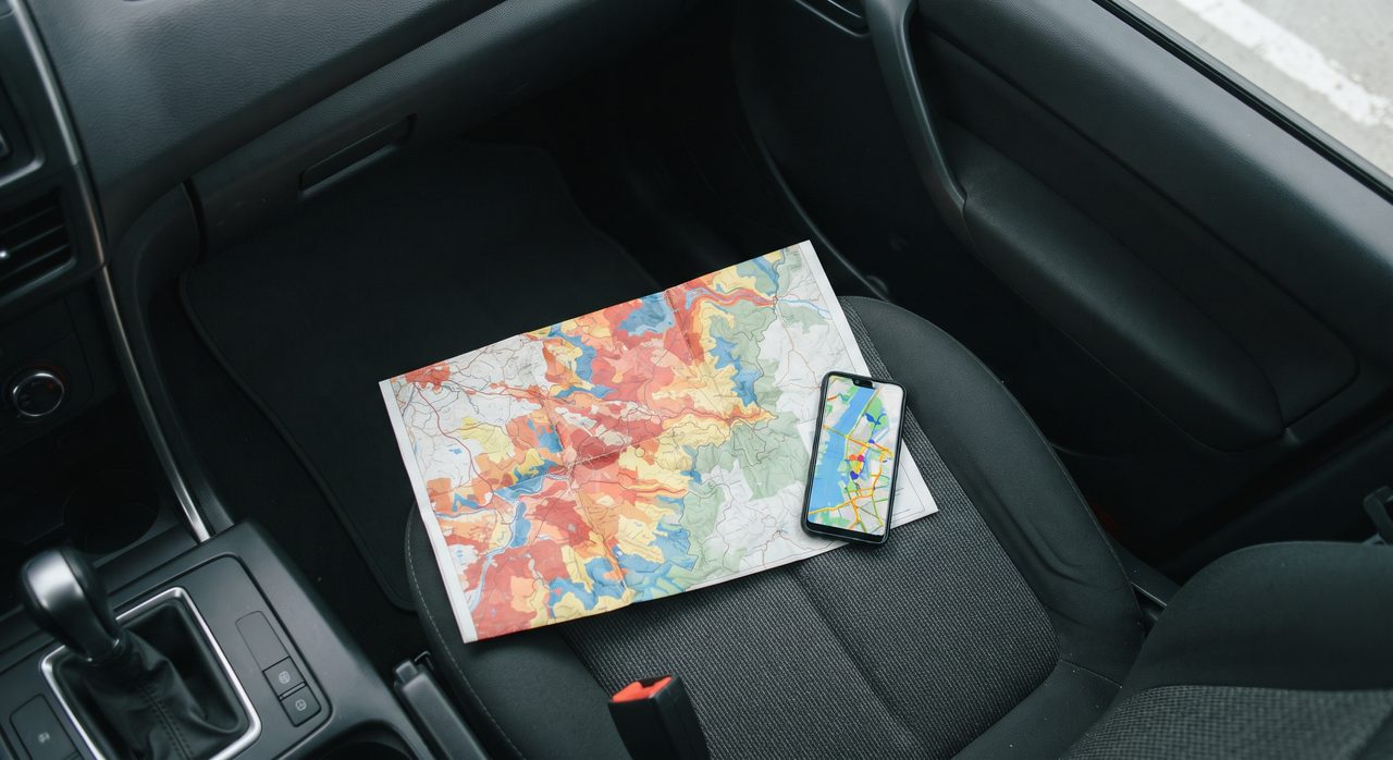 車の助手席に紙のハザードマップと地図アプリを表示したスマートフォンが並べて置かれている様子