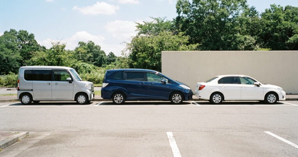 明るい駐車場に並ぶ軽自動車・ミニバン・セダンの3タイプの側面シルエット比較